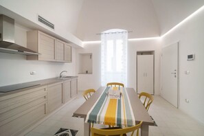Una cocina moderna con comedor, una ventana con cortinas y una mesa con mantel a rayas.