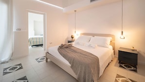 Een slaapkamer met een bed, nachtkastjes, een lamp en een deur naar een andere kamer.