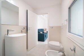 Un baño moderno con lavamanos grande, inodoro y espejo.