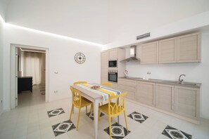 Une cuisine de taille réduite comprenant une table à manger, des chaises, une horloge et un four à micro-ondes.