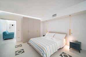 Une chambre moderne avec un grand lit, une armoire, une table de chevet et un canapé.