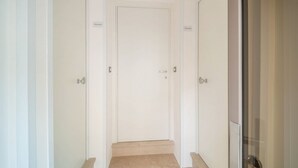 A narrow hallway with a closed door at the end, flanked by two doors on either side. - WePuglia - The White Luxury – Apt Ataraxia (Monopoli)