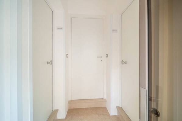 A narrow hallway with a closed door at the end, flanked by two doors on either side. - WePuglia - The White Luxury – Apt Ataraxia (Monopoli)