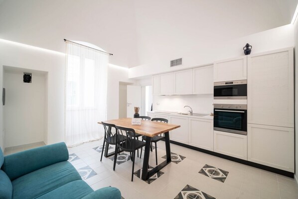 A modern kitchen with white cabinets, a wooden dining table, and black chairs.