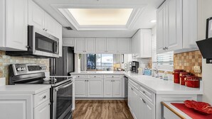 Una cocina moderna con armarios blancos, electrodomésticos de acero inoxidable y piso de madera.