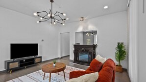 A modern living room with a flat-screen TV, a fireplace, a sofa, and a coffee table.
