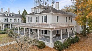 A large, two-story white house with a covered porch and multiple chimneys.