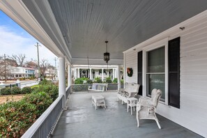 A covered porch with white wicker furniture, a hanging lantern, and a view of the neighborhood. - Charming 1-bedroom condo in idyllic Washington~Walk to Waterfront! (Washington)