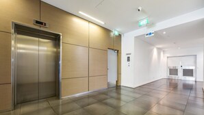 A modern elevator, a residential intercom, and a hallway with a clean, tiled floor. - 15th Floor Superior Hotel Suite King Bed (Darwin City)
