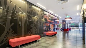 A modern hotel lobby with a large wall mural, seating areas, and a visible pharmacy. - 15th Floor Superior Hotel Suite King Bed (Darwin City)