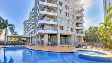 Un hotel su più piani con piscina e area salotto all'aperto.