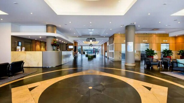 A spacious lobby with a central circular design, a reception desk, seating area, and a modern ceiling with recessed lighting. - Resort Style City View w/ King Bed, Pool, Balcony (Darwin City)