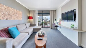 A modern hotel room with a sofa, a coffee table, a TV, and a city view. - Resort Style Escape w/ King Bed, Pool, Balcony (Darwin City)