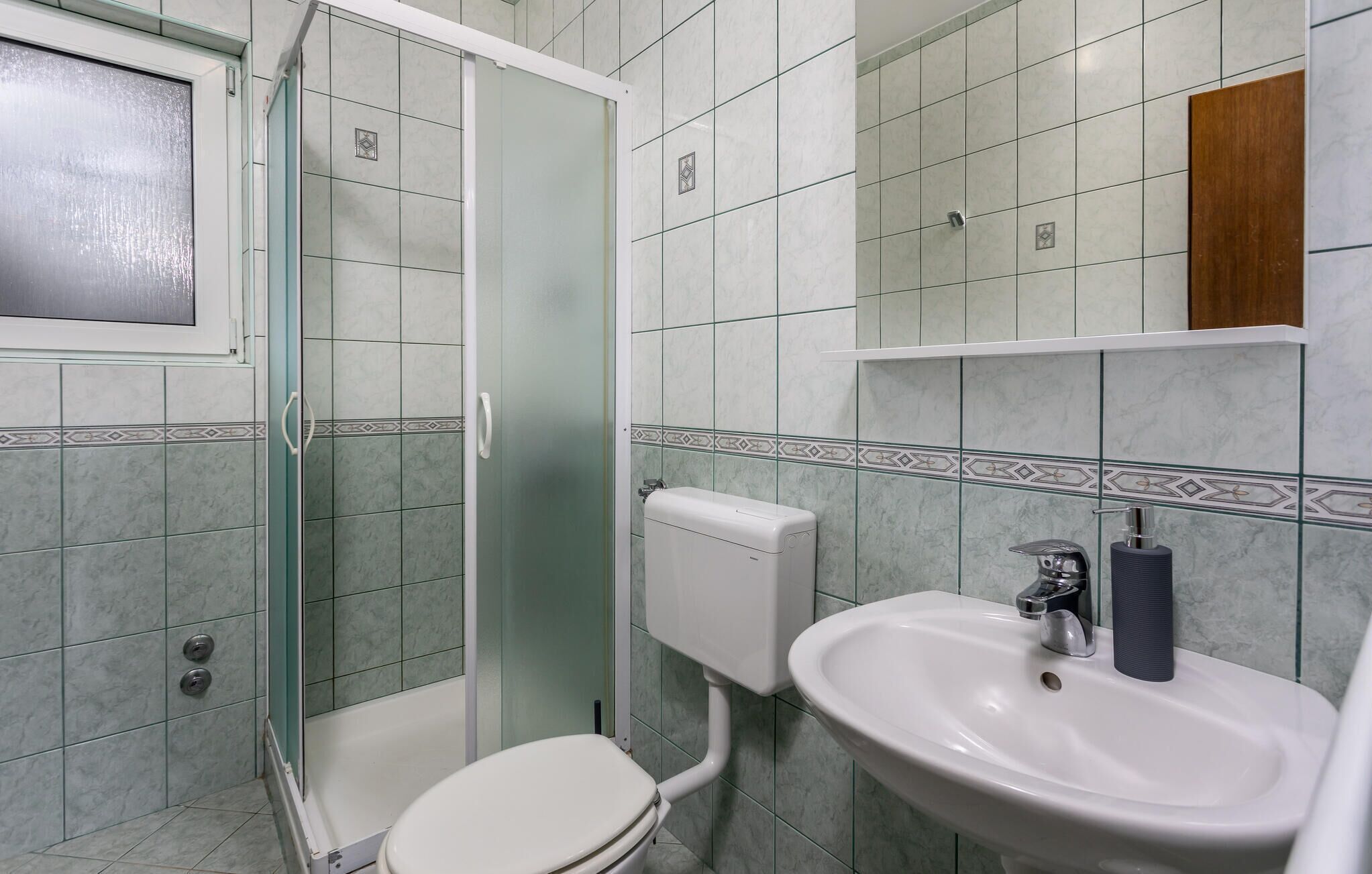 A bathroom with a toilet, sink, and shower.