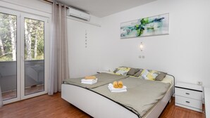 A modern bedroom with a bed, a bedside table, a nightstand, and a window with curtains. - Nice apartment in Lopar with house sea view (Lopar)