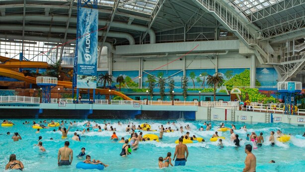 Een groot binnenzwembad met meerdere banen en een waterglijbaan.
