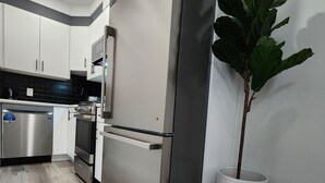 Een moderne keuken met roestvrijstalen apparatuur, witte kasten en een houten vloer.