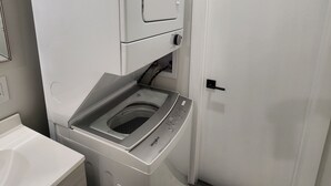 Een kleine wasruimte met een voorlader wasmachine, een droger en een deur.