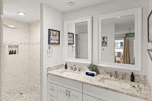 Enjoy a refreshing bathroom experience with a dual sink vanity, large mirror, and shower area.