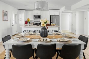Enjoy meals in this stylish dining area with a table for six, a vase of fresh flowers, and a warm ambiance.