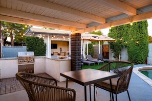 Enjoy al fresco dining and relaxation in this outdoor space with a grill, table, and seating area.