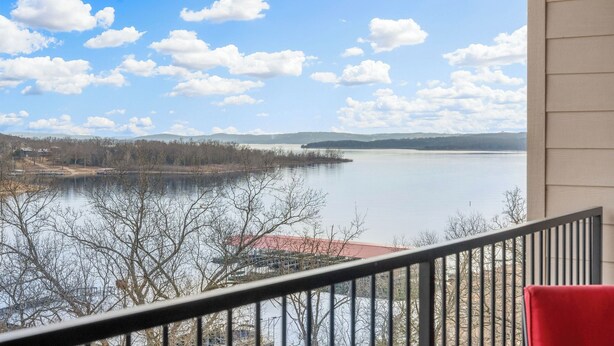 En balkon med udsigt over en sø og fjerne bjerge.