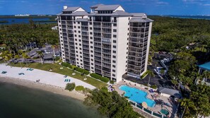 A high-rise hotel with multiple balconies, a pool, and a beach area.