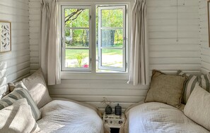 Ein gemütliches Zimmer mit großem Fenster, zwei Betten und einem kleinen Tisch mit Dekoration.