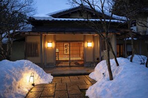 Un bâtiment traditionnel japonais, avec une entrée enneigée et une porte en bois.