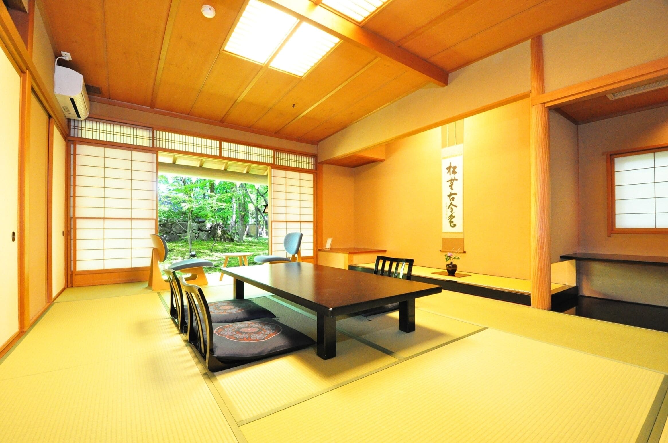 A traditional Japanese room with tatami flooring, a low table, and a sliding door leading to a garden.