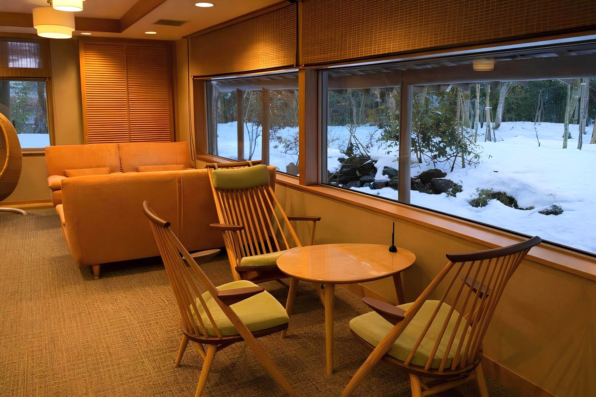 A cozy seating area with a sofa and chairs, a round table, and a large window with a snowy view.