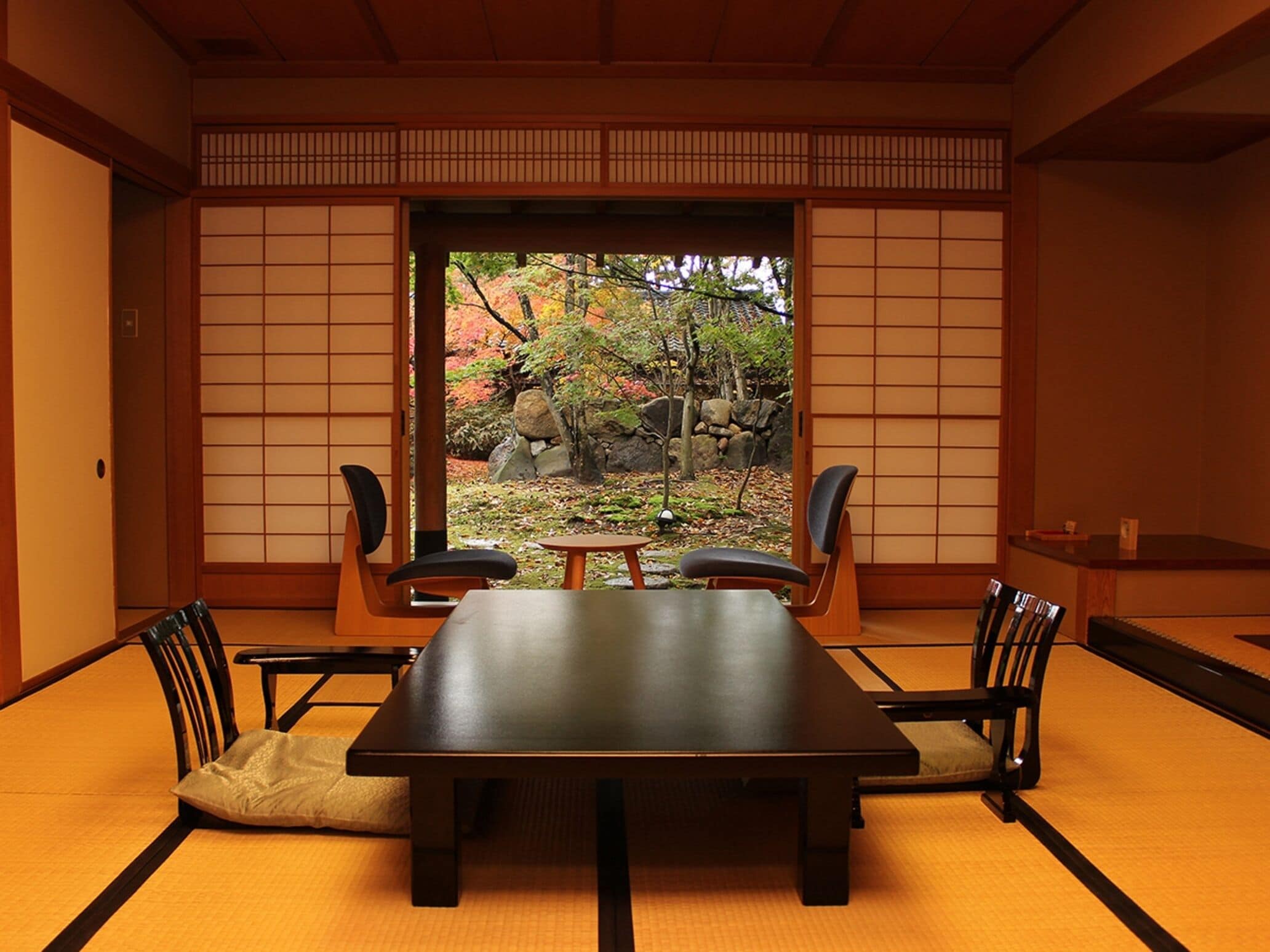Une pièce de style japonais traditionnel, avec un sol recouvert de tatamis, une table basse et quatre chaises.