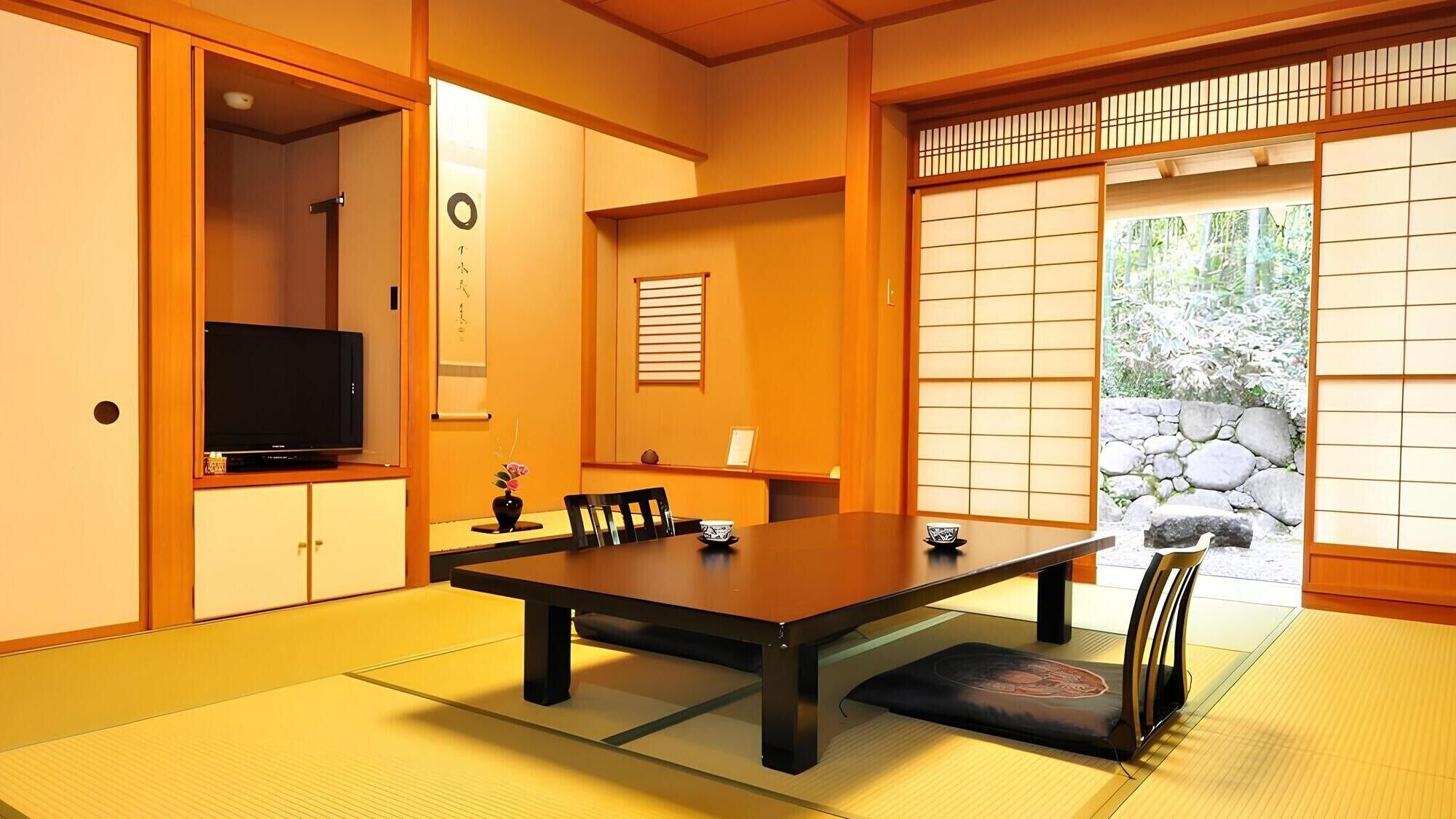 Una habitación japonesa tradicional con suelo de tatami, una mesa baja y puertas correderas.
