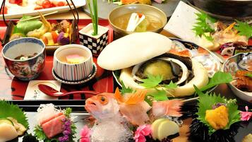 Eine traditionelle japanische Mahlzeit mit verschiedenen Gerichten, darunter rohes Fischfilet, eine Suppe und ein heißes Topfgericht.