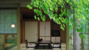 Una habitación japonesa tradicional con suelo de tatami, una mesa baja y un televisor montado en la pared.