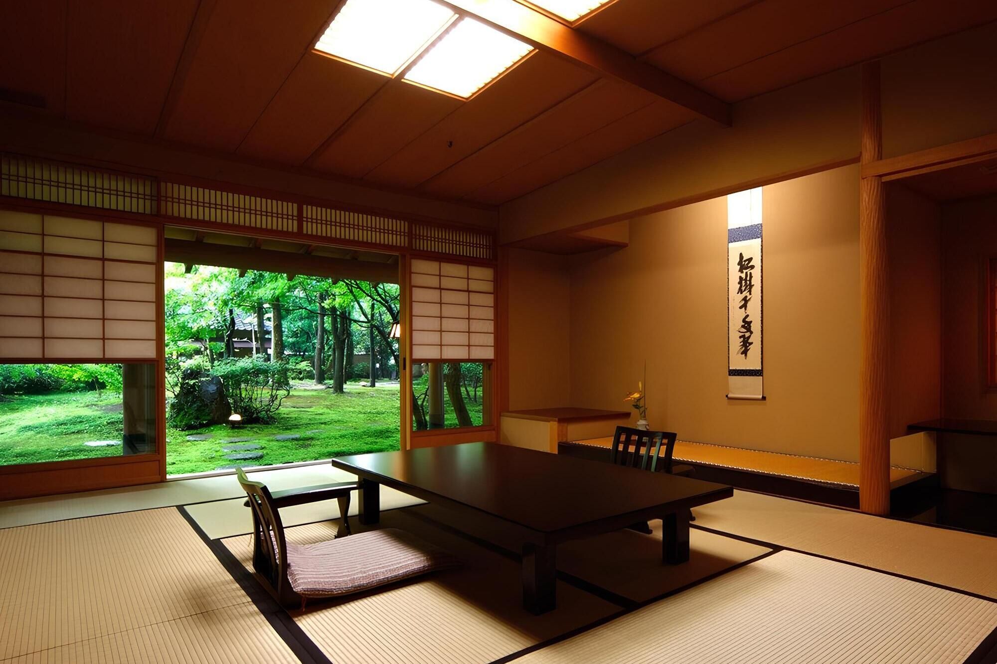 Ein traditioneller japanischer Raum mit Tatami-Böden, einem niedrigen Tisch und Schiebetüren, die zu einem Garten führen.