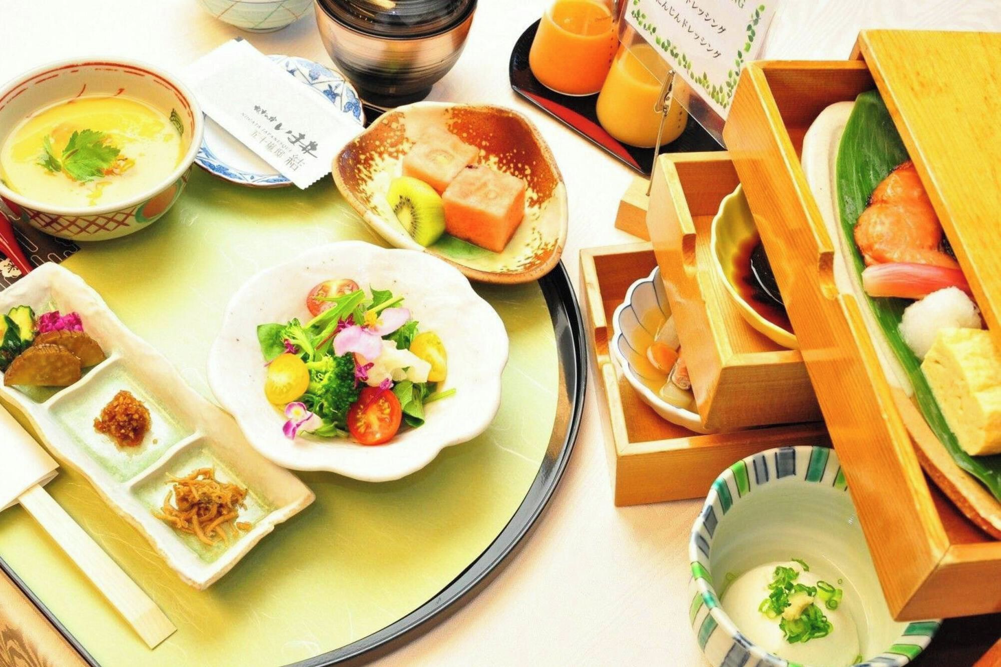 Une variété de plats, notamment de la soupe, de la salade et des sushis, présentés sur un plateau.