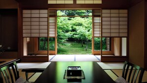 Una habitación japonesa tradicional con suelo de tatami, una mesa baja y puertas correderas que dan a un jardín.