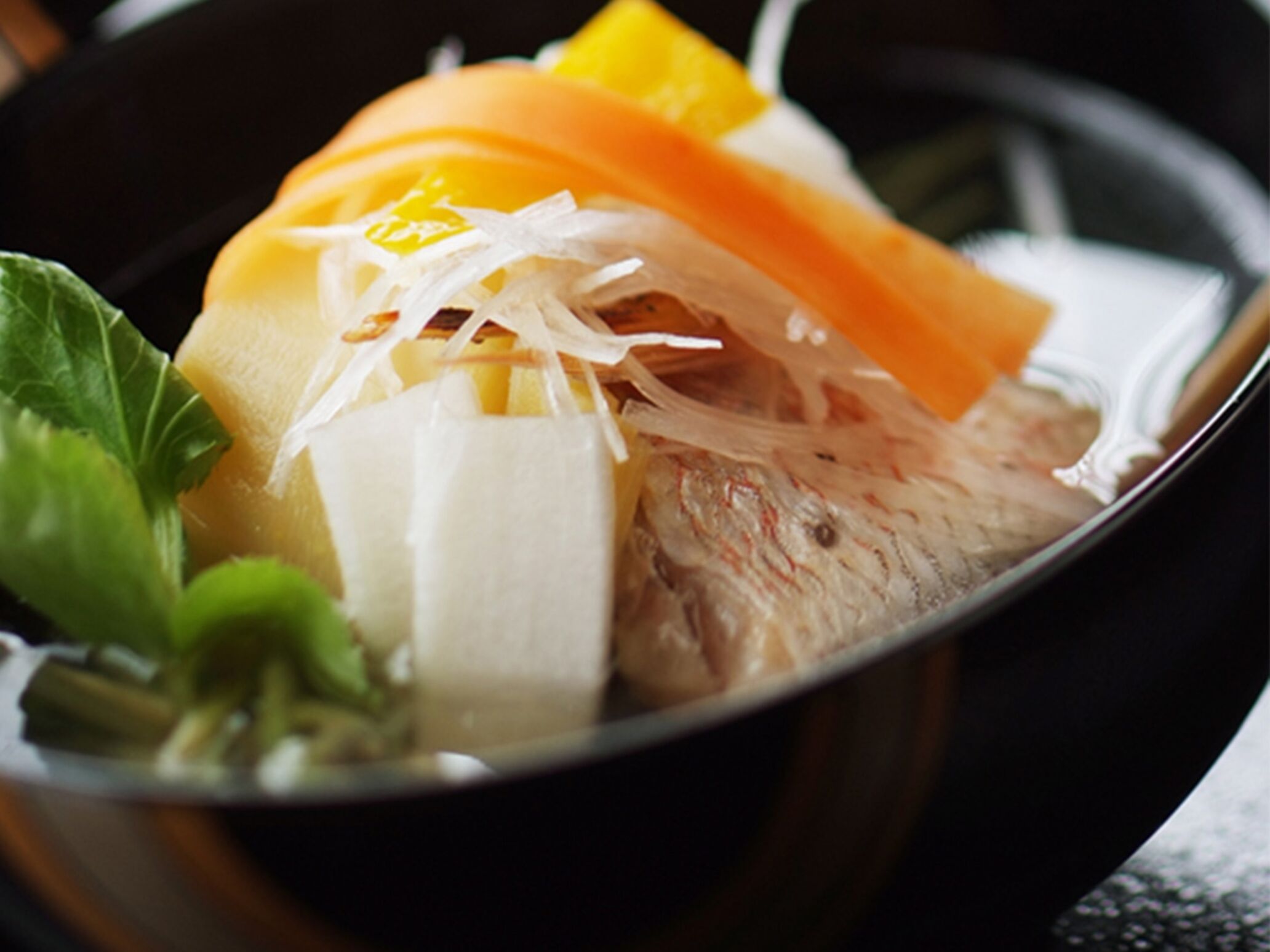 Un tazón de sopa con verduras y pescado.