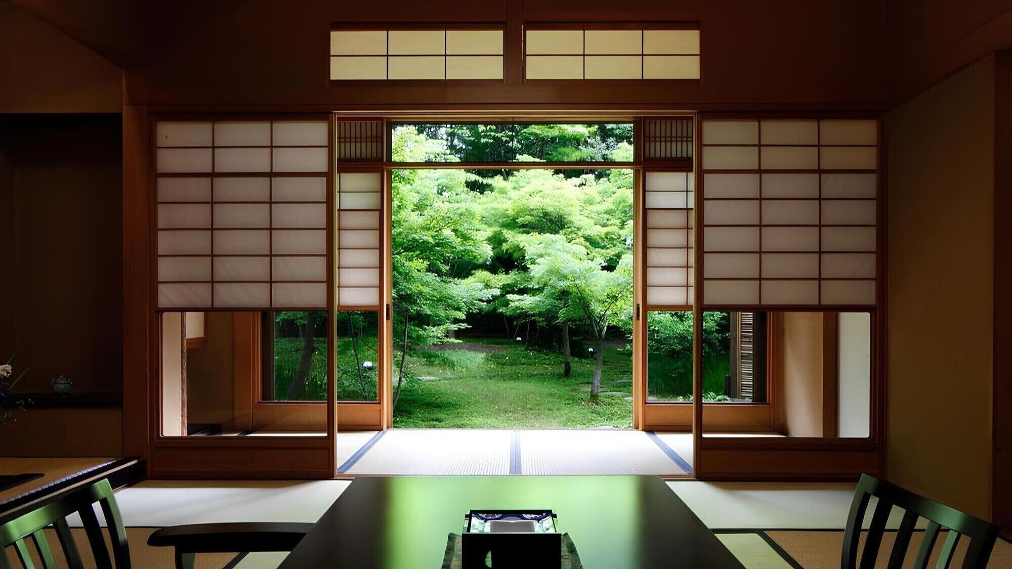 Una habitación japonesa tradicional con suelo de tatami, una mesa baja y puertas correderas shoji.