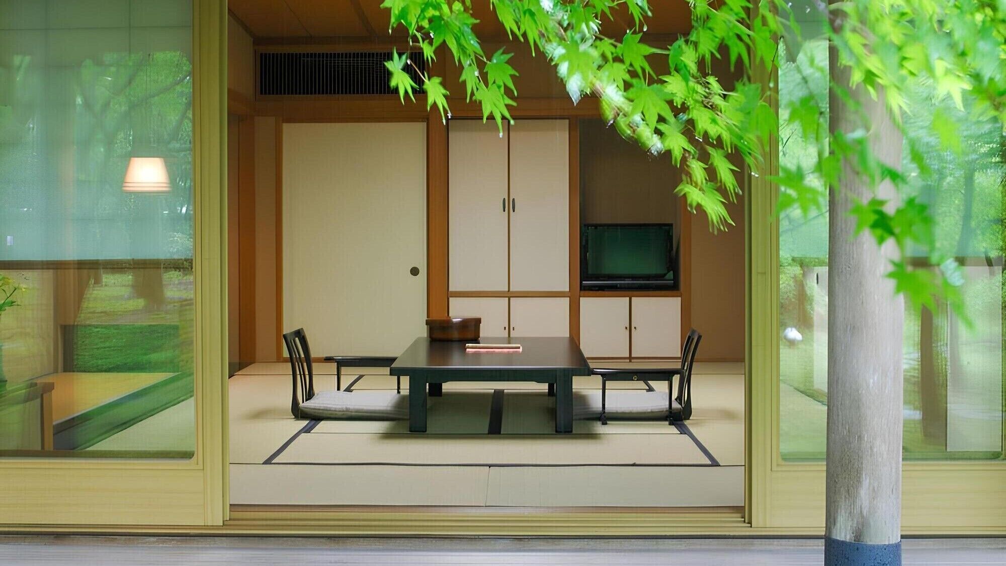 Una habitación japonesa tradicional con suelo de tatami, una mesa baja y sillas.