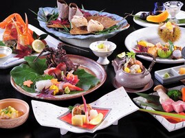 Una variedad de platillos sobre una mesa, incluyendo mariscos, verduras y frutas, dispuestas en diferentes platos y fuentes.