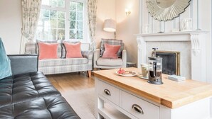 Een gezellige woonkamer met een bank, een fauteuil, een salontafel en een open haard.