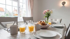 Een ontbijttafel met croissants, sap en een vaas met bloemen.
