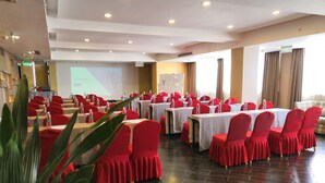 A conference room with tables and chairs, a projector screen, and a presentation area. - HOWDY SMART HOTEL (Chengdu)
