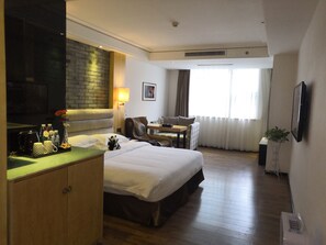 A hotel room with a bed, a desk, a massage chair, a TV, and a window with curtains. - HOWDY SMART HOTEL (Chengdu)