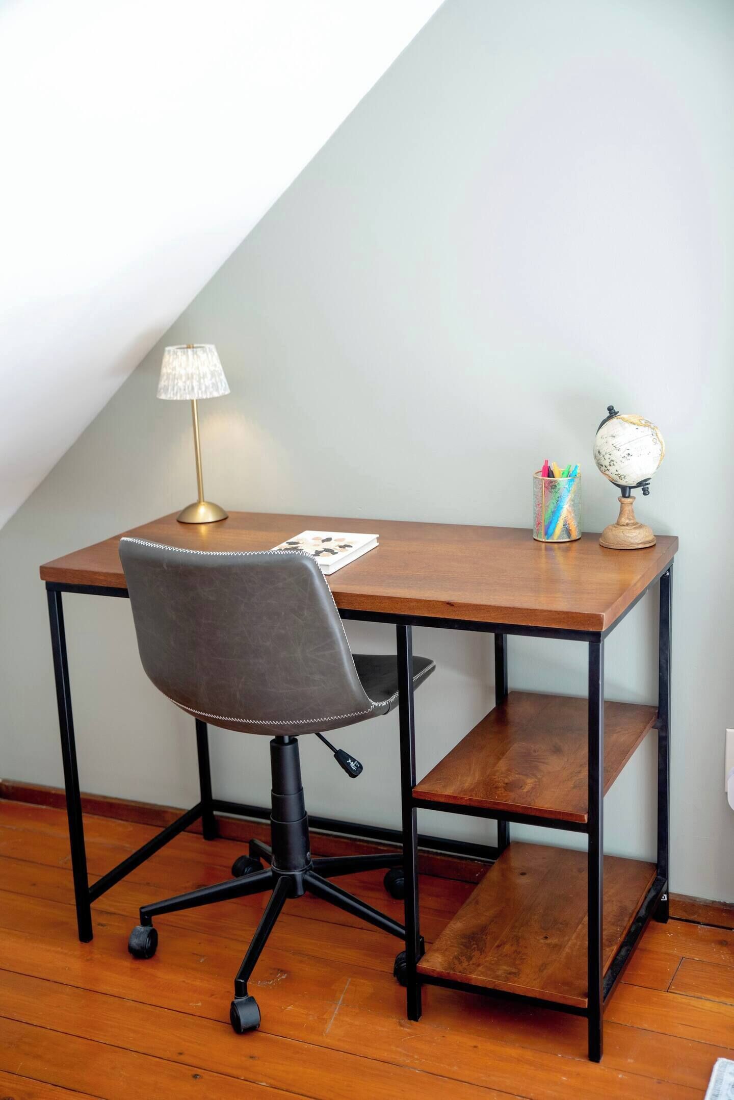 Ein Schreibtisch mit Stuhl, Lampe, Globus und Stifthalter.