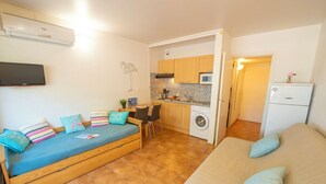 Ein gemütlicher Wohnraum mit einer Couch, einem Bett, einer Waschmaschine und einer Küchenzeile.