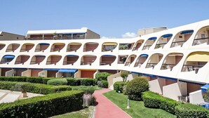 Ein mehrstöckiges Hotel mit Balkonen, einer zentralen Fußgängerzone und gepflegter Bepflanzung.