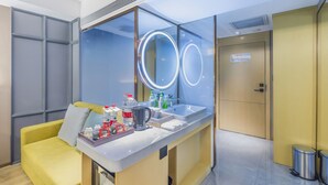 A modern hotel room with a yellow sofa, a large mirror with illuminated circles, a sink, and toiletries on the counter. - Lidu International Hotel (Handan)